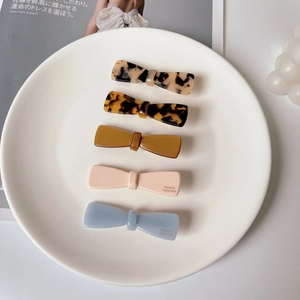 Set of 5 acetate bow hair clips in tortoiseshell and pastel colors on white plate