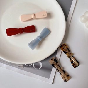 Detailed shot of acetate bow hair clips and tortoiseshell barrettes on a ceramic plate