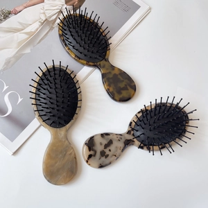 Three acetate hairbrushes with tortoiseshell patterns and massage air cushions on a magazine