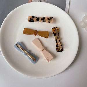 Handmade acetate hair clips set featuring colorful bow designs on a minimalist plate