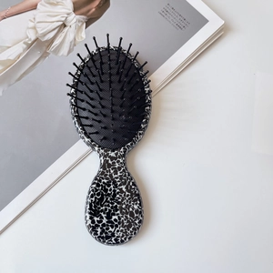 Detail view of oval hair brush with animal print handle on a lifestyle magazine background