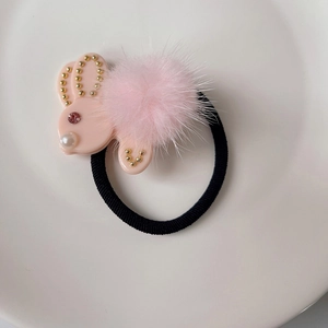 Dettaglio dell'elastico per capelli con coniglio rosa, accenti dorati e morbido pompon