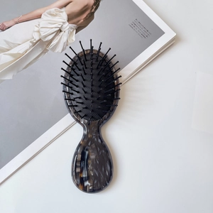 Detail of gray marble texture massage hairbrush with nylon bristles on a white desk