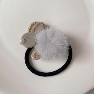 Dettaglio dell'elastico per capelli a coniglio in peluche con perle e borchie d'oro