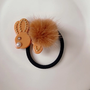 Dettaglio dell'elastico per capelli con coniglio di peluche arancione e perle finte