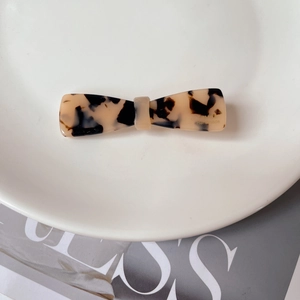 Detailed macro view of an acetate tortoiseshell bow hair clip with gold handmade lettering