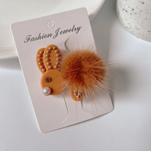 Dettaglio del fermaglio per capelli a coniglio con coda di peluche, perla e strass