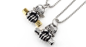Close-up of fist holding dumbbell pendant in silver and gold tone stainless steel