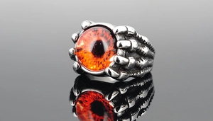 Macro detail of gothic silver dragon claw ring clutching a fiery orange evil eye