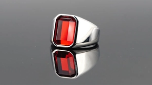Gros plan d'une bague pour homme en acier avec une pierre rouge carrée imposante