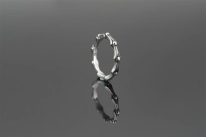 Detail of gothic silver ring with bone structure design on reflective black surface