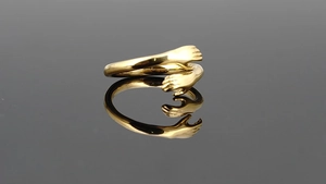 Detailed view of hug-shaped gold-plated stainless steel ring with polished finish