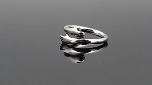 Macro detail of silver-tone embrace hug ring with polished finish and reflection