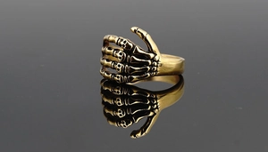 Detailaufnahme des retro goldenen Totenkopfrings mit Punk-Rock Skelett-Gelenken und Gravur