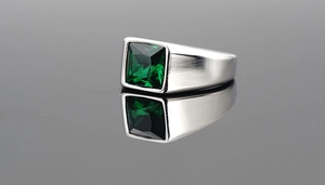 Macro shot of silver titanium ring with square green gemstone and polished finish