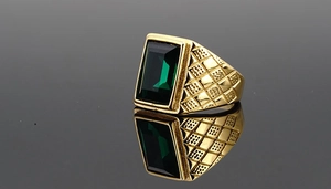Macro shot of men's vintage gold ring with rectangle green gemstone and textured band