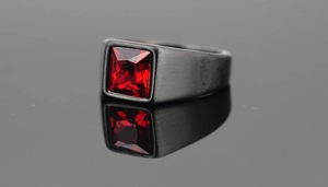 Detail of men's black brushed titanium ring with square red faceted gemstone