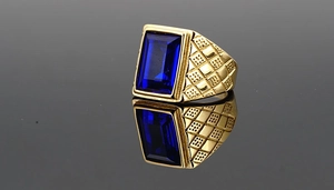Macro shot of gold plated men's ring featuring a deep blue stone and checkered side texture