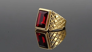 Macro detail of men's gold vintage ring featuring red rectangle gemstone and textured band