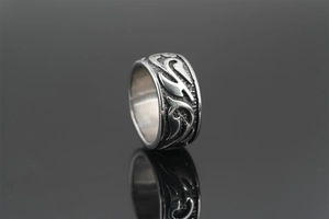 Gros plan d'une bague vintage en acier titane avec motif de flamme sur fond noir réfléchissant