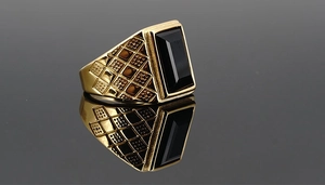 Close-up of gold-plated signet ring for men with black gemstone and textured pattern