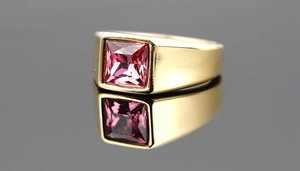 Macro shot of square pink gemstone set in a thick polished gold-plated titanium ring