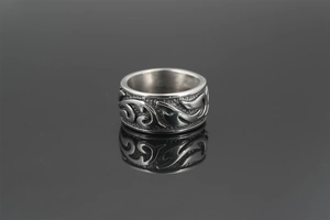 Gros plan d'une bague vintage en acier titane avec totem de flammes et fini oxydé