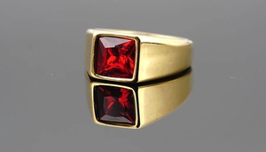 Detailed macro view of a gold-plated signet ring featuring a square-cut red gemstone inlay
