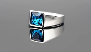 Macro shot of brushed silver titanium ring featuring a square blue sapphire gemstone inlay
