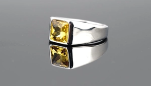 Macro shot of silver titanium ring featuring a square yellow crystal with mirror reflection