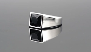 Macro shot of silver titanium ring with square black onyx stone and brushed metal texture