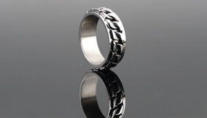 Macro shot of silver rotating Cuban chain ring with polished edges on a black mirror