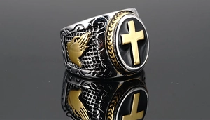 Detail of cross signet ring featuring praying hands engraving and golden relief