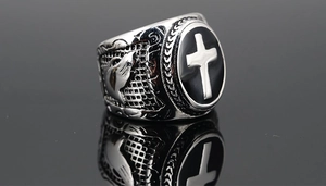 Close-up of vintage titanium steel ring with black enamel cross and praying hands detail