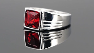 Makroaufnahme eines Edelstahlrings mit quadratischem rotem Edelstein und Stufendetails