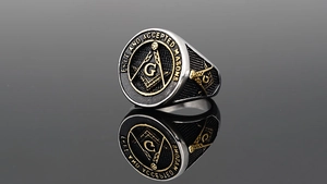 Macro shot of silver Freemason signet ring with gold square and compass on black enamel