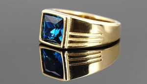 Detail eines goldenen Siegelrings mit quadratischem Saphir und seitlichen Rillen