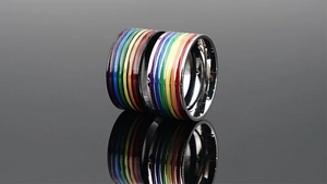 Makroaufnahme von Edelstahl-Regenbogen-Emaille-Ringen, die auf schwarzem Spiegel spiegeln