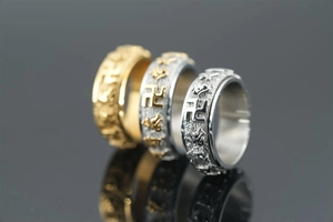 Detail view of rotating titanium rings with gold and silver Buddhist mantra engravings