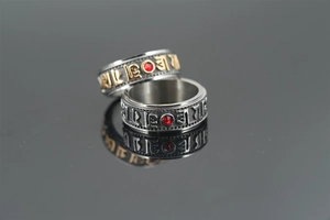 Detailed macro view of rotating stainless steel rings with red zircon and religious symbols