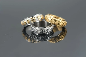 Detail view of rotating stainless steel rings with engraved Buddhist mantra symbols