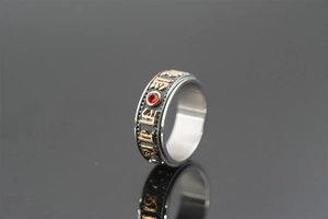 Macro detail of rotating titanium steel ring with mantra engraving and red crystal inlay