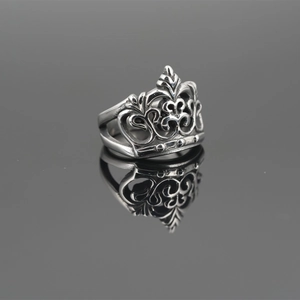 Vintage stainless steel crown ring featuring hollowed-out carvings on a grey mirror surface