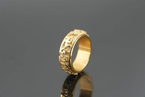 Detailed view of the rotating Buddhist mantra ring with golden relief engraving and swastika symbols
