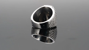 Macro shot of silver ring with textured grainy exterior and polished inner band