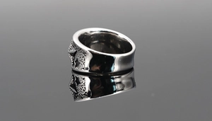 Gros plan d'une bague vintage en acier avec étoiles en relief et finition texturée
