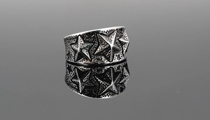 Vue détaillée d'une bague large argentée vintage avec motifs d'étoiles en relief et texture martelée