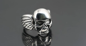 Makroaufnahme des silbernen Totenkopfrings mit detaillierten Flügeln und Politur
