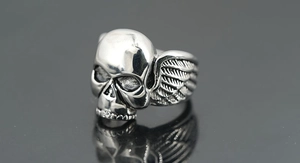 Makroaufnahme eines Punk-Totenkopfrings mit Flügeldetails und poliertem Edelstahl-Finish