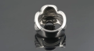 Makroansicht eines breiten Silber-Totenkopfrings mit innerer Hohlstruktur und Metalltextur